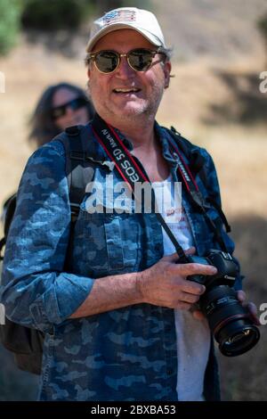 A man poses with his Canon DSLR while on a hike in Yolo County, CA. Stock Photo