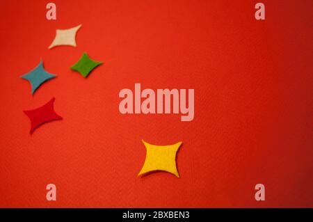 There are 5 rectangular colored stars on red cardboard. For background, with place for text Stock Photo