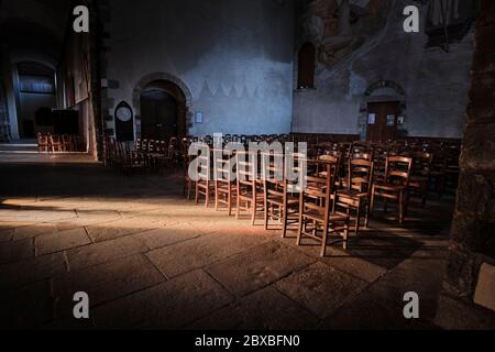 Wooden chairs and kneeling stools in the Transpet of the Church of St. Melaine with a stream of light illuminating the chairs and alcove Stock Photo