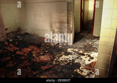 Interior of an abandoned building after a fire. View of a room, the hallway and the bathroom burned and full of rubble. Stock Photo