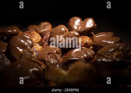 Chocolate palmier biscuits low light. Heart-shaped puff pastry, pig's ear, palm leaves cookies, elephant ears, french hearts, shoe-soles. Stock Photo