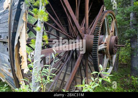 Rusty pieces of mining machinery are being swallowed by the forest in the Elkhorn mining district of Montana near the ghost town of Coolidge. Stock Photo