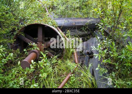 Rusty pieces of mining machinery are being swallowed by the forest in the Elkhorn mining district of Montana near the ghost town of Coolidge. Stock Photo