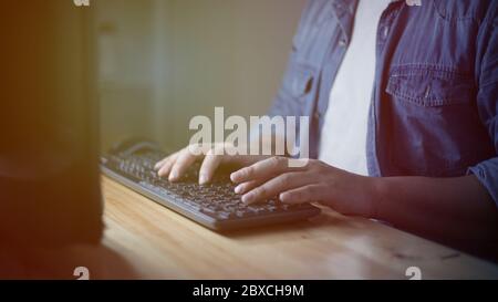 Male anonymous businessman entrepreneur working overtime alone in a dark office at the evening, work hard for his ambition of success Stock Photo