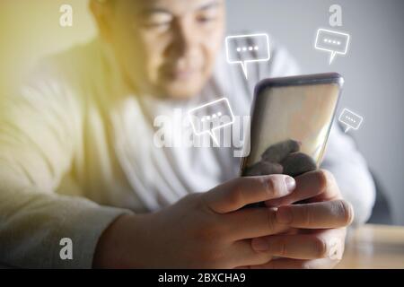Asian man sending text message and sms with smartphone. Guy texting and using mobile phone late at night in dark. Communication or sexting concept. Ch Stock Photo