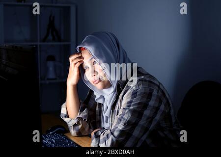 Frustrated sad woman feeling tired worried about problem when looking at computer in the dark at night, stressed depressed girl troubled with reading Stock Photo