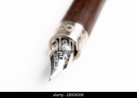 A close-up product shot of the wooden barrel and writing tip of a classic fountain pen set on plain white background. Stock Photo