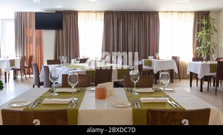 Table ready for guests in interior restaurant with brown curtains Stock Photo