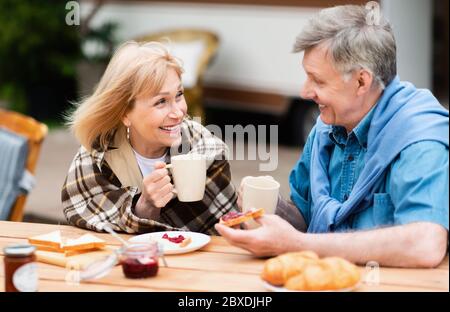 Affectionale elderly couple having coffee with toasts and jam for lunch in countryside Stock Photo