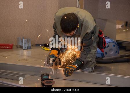 Beautiful yellow sparks from the rotation and cutting of metal by hand grinder as background Stock Photo