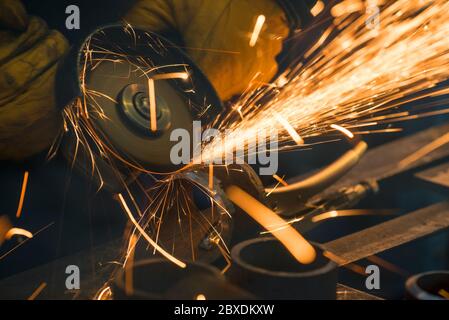 Beautiful yellow sparks from the rotation and cutting of metal by hand grinder as background Stock Photo