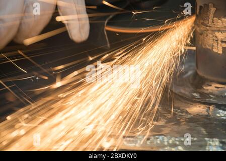 Beautiful yellow sparks from the rotation and cutting of metal by hand grinder as background Stock Photo