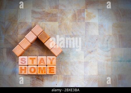 Stay home to stay safe due to Covid-19 coronavirus outbreak pandemic. Concept of self isolation or quarantine message engraved on wooden blocks on woo Stock Photo