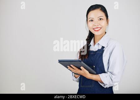 Portrait of beautiful smiling young cafe owner using tablet computer to track orders Stock Photo