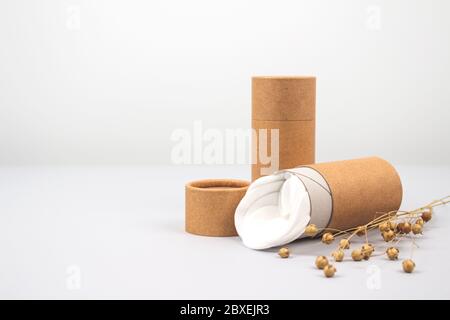 Front view on paper tubes with white cotton disks inside on light grey background with copyspace. Reusable packaging and recycling concept showing how Stock Photo