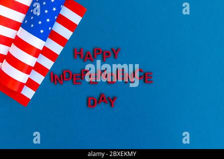 Text happy Independence Day wooden red letters. Wavy American flag .Top view. Stock Photo