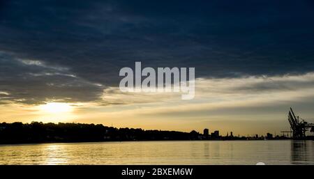 Hamburg, Germany. 07th June, 2020. The sun rises behind dark rain clouds over the Hamburg harbour. Credit: Axel Heimken/dpa/Alamy Live News Stock Photo