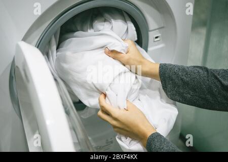 A woman or a housewife loads or puts the laundry in the dishwasher for washing. Stock Photo