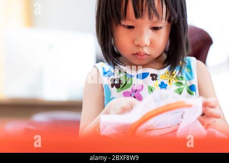 Asian girl child sewing in living room at home as home schooling while city lockdown because of covid-19 pandemic across the world. Home Scholling pre Stock Photo