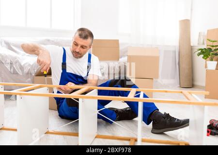 Furniture Assembler Installing Shelf After Relocation Sitting On Floor Indoors Stock Photo