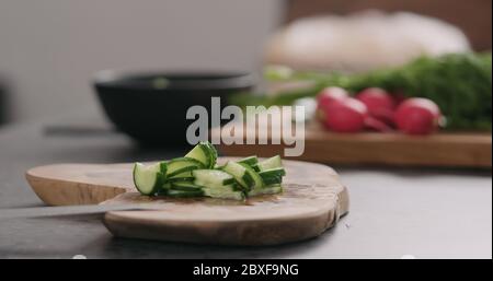 man takes sliced cucumber from olive board side view Stock Photo