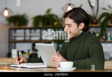 Freelancer working on new project at cafe, using digital tablet Stock Photo