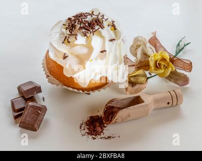 A tasty cupcake covered with cream and chocolate chips with beautiful decoration on a white background Stock Photo