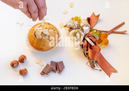 A delicious muffin is covered with white almond flakes with a nice decoration next to it on a white background Stock Photo