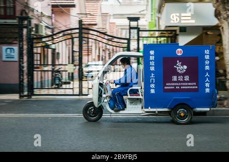 An electric household food waste tuktuk goes past lane houses on Shanghai’s Jiaozhou Road. Stock Photo