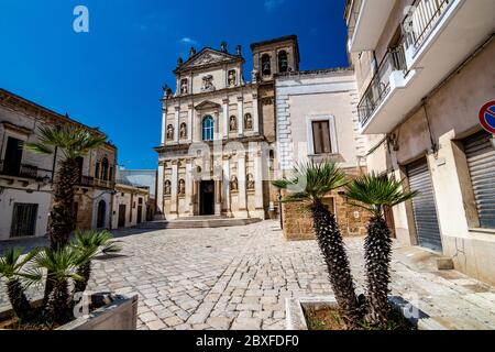 The old church of St. Anna, Mesagne. Puglia, Italy under the clear blue sky of a sunny summer day, travel photography, street view with few beautiful decorative palm trees in foreground Stock Photo