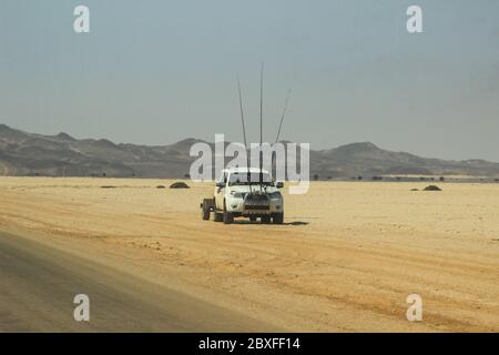 Sossusvlei, Namibia - April 28, 2015: Desert landscapes with mountains, road and car with fishing rods in the south of Namibia. The dry season, dry ve Stock Photo