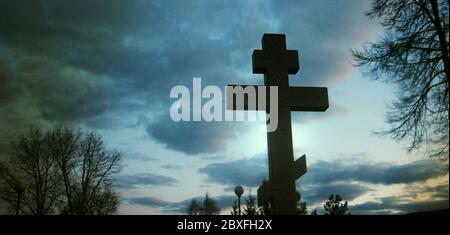 Cross in cemetry in evening under stormy sky. Life and death concept Stock Photo