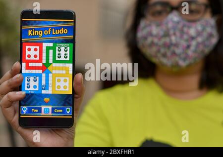 New Delhi, India, 2020. Girl wearing surgical face mask showing Ludo King game app on her mobile phone screen. Due to Corona Virus (covid-19) disease Stock Photo