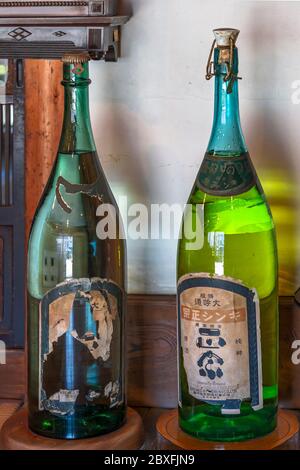 tokyo, japan - march 31 2020: Two old pressure cap glass bottles of japanese sake with a torn label of Kinshi Masamune in the ancient   Yoshidaya liqu Stock Photo