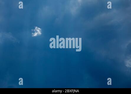 One tiny white cloud on dark grey sky Stock Photo