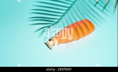 Orange container for cosmetics without label lies on turquoise background Stock Photo