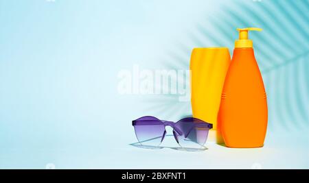 Orange containers without label for lotion, purple glasses on blue background, space for text Stock Photo