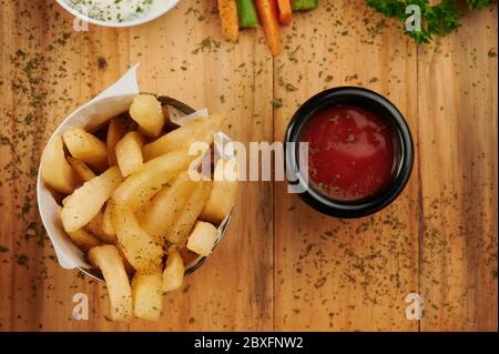 French fries in cup with tomato sauce on wooden background Stock Photo