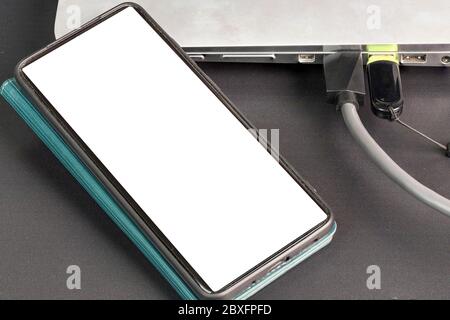 Close up view of  connecting usb cable  mobile phone with mockup image blank screens and usb flash drive  to silver notebook computer. Stock Photo