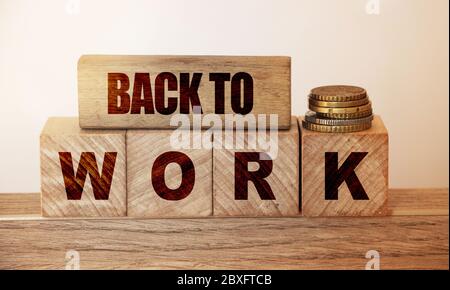 Wwooden blocks reading Back To Work and pill of coins on it. Salary earning concept, earn more money business concept