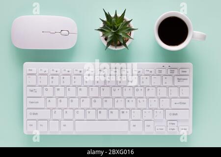 office workplace, computer keyboard with coffee cup, evenly arranged objects, bright colors, top view Stock Photo