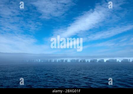 A large iceberg floating in  Antarctica, covered in fog. Stock Photo
