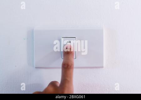 Close up of finger is turning on or off on light switch. Stock Photo