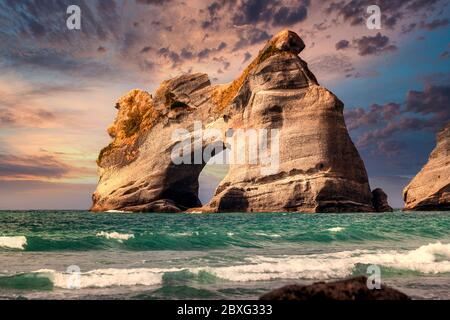 Amazing sunset over famous rock formations on the Wharariki beach in National Park. Nelson, South Island, New Zealand. Stock Photo
