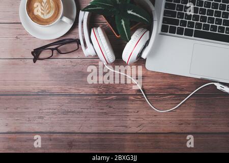 Computer laptop with headphones and latte art hot coffee on wooden table. top view and copy space for in put text. work from home and new normal conce Stock Photo