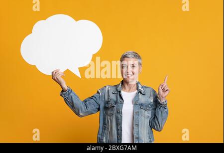 Idea Concept. Mature Woman Holding Empty Speech Bubble And Pointing Finger Up Stock Photo
