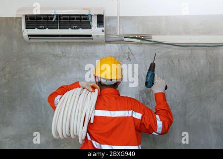 Technician installing air conditioner on the wall, Thailand Stock Photo
