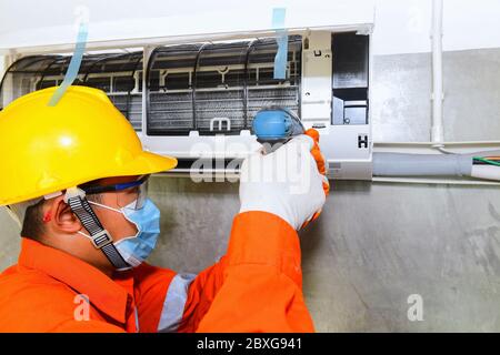 Technician installing air conditioner on the wall, Thailand Stock Photo