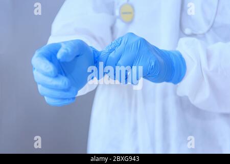 Doctor wearing PPE putting on surgical gloves, Thailand Stock Photo