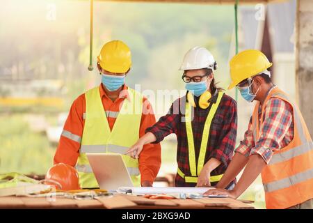 Three engineers on a building site wearing face masks, Thailand Stock Photo